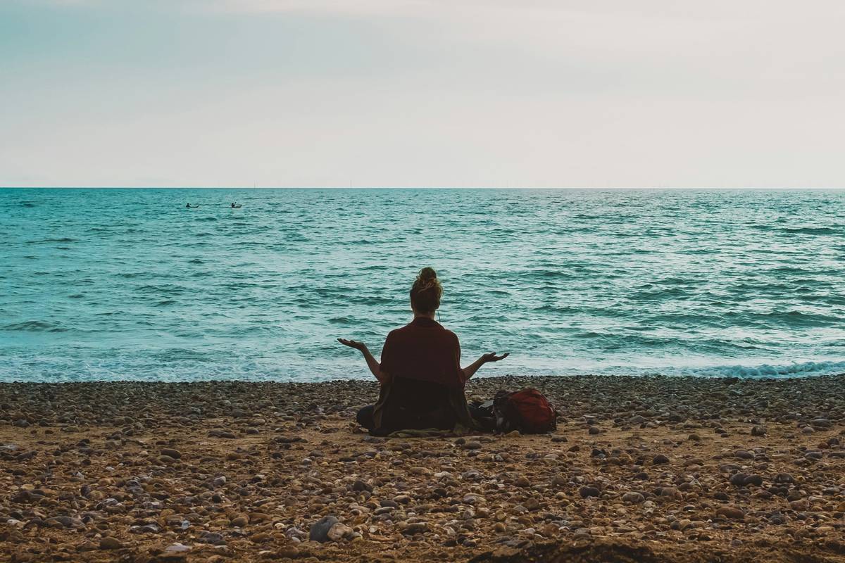Woman sitting calmly by a window at dawn practicing peaceful mindset tips
