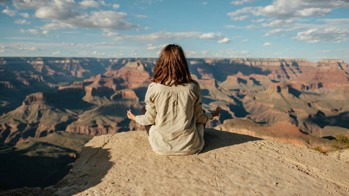 Woman practicing peacefulness habits while sitting calmly by a window with morning light