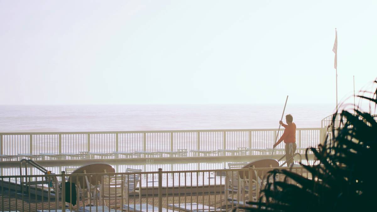 pool guy cleans oceanfront pool in morning mist